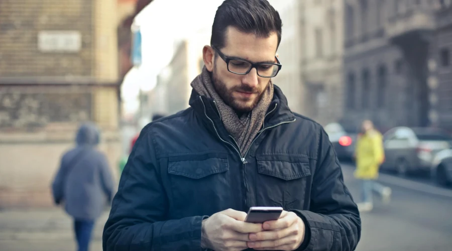 Man Wearing Black Zip Jacket Holding Smartphone